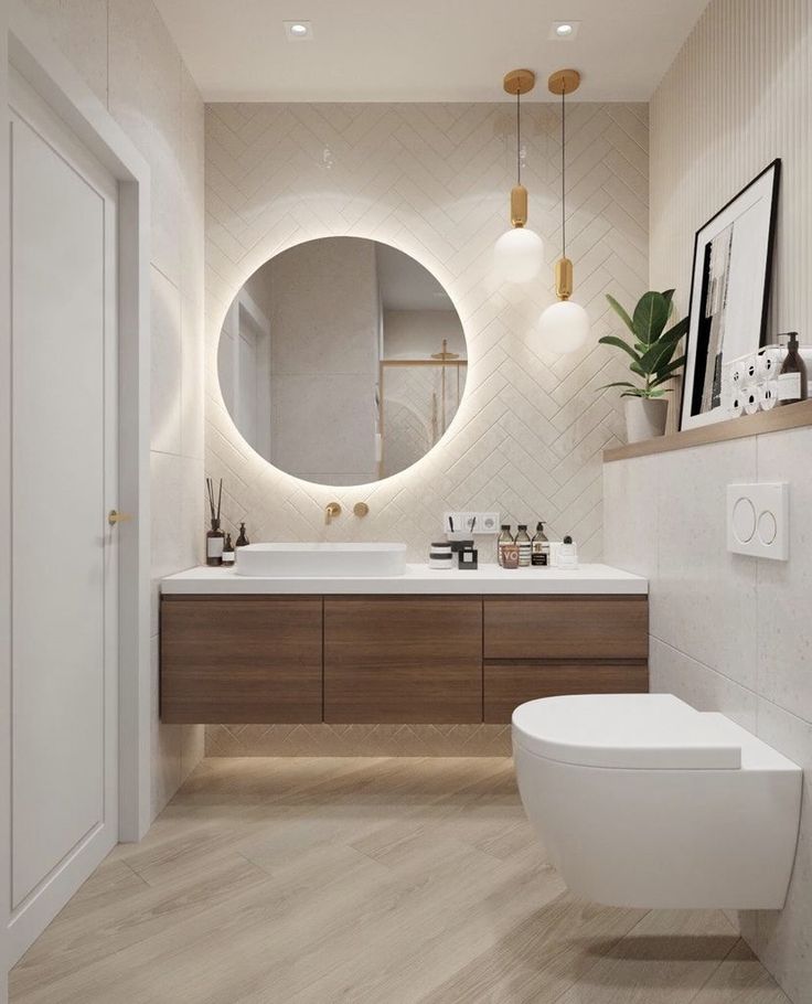 a white toilet sitting next to a bathroom sink under a round mirror on a wall