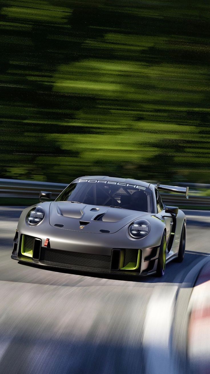 a silver sports car driving on a track with blurry trees in the back ground