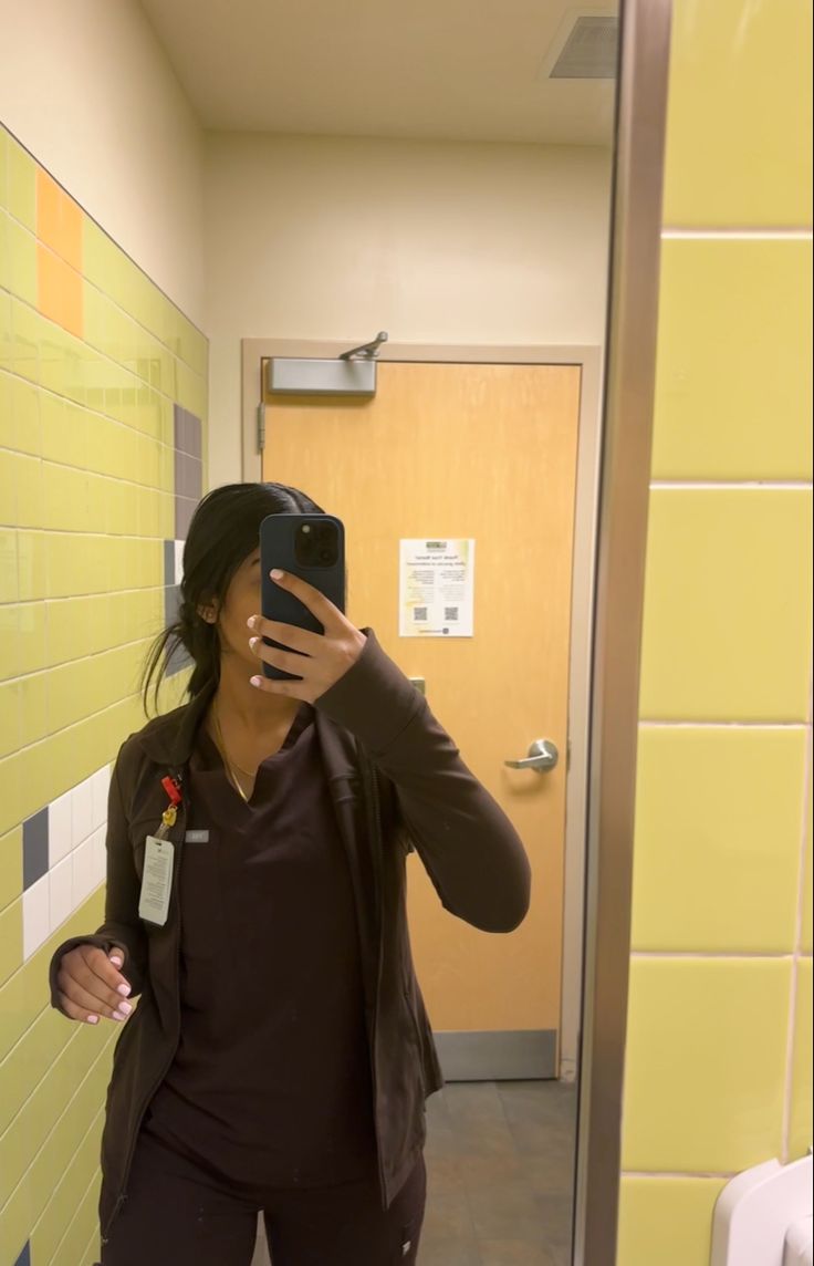 a woman taking a selfie in a bathroom mirror