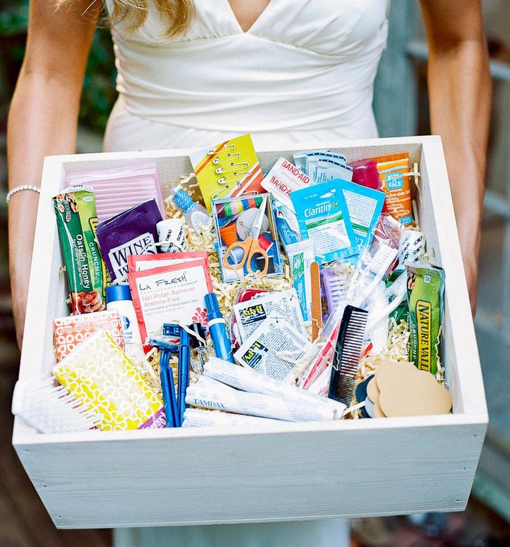 a woman holding a white box filled with lots of different types of candy and candies