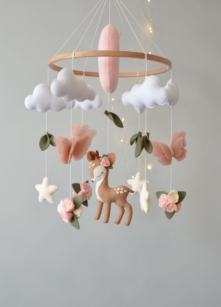 a baby mobile with pink and white decorations hanging from it's sides, in the shape of a deer