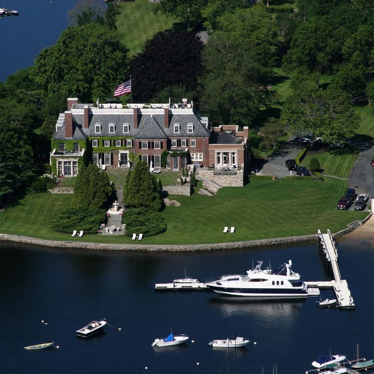 an aerial view of a large house with boats in the water