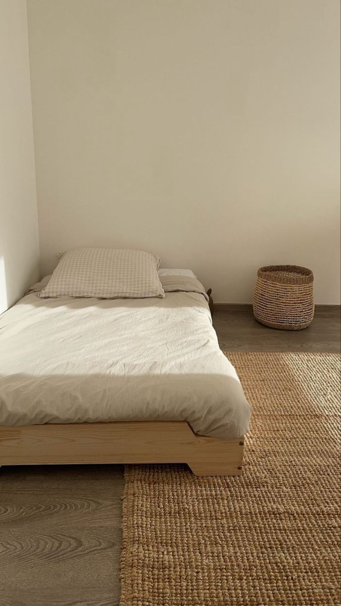 a bed sitting on top of a wooden floor next to a basket