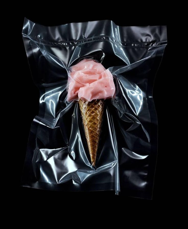 an ice cream cone is wrapped in black plastic and has a pink flower on top