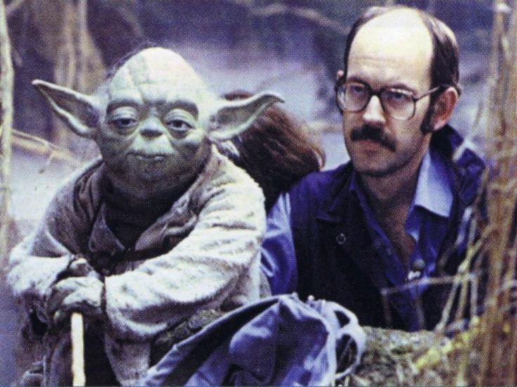 a man with glasses and a moustache next to yoda star wars character