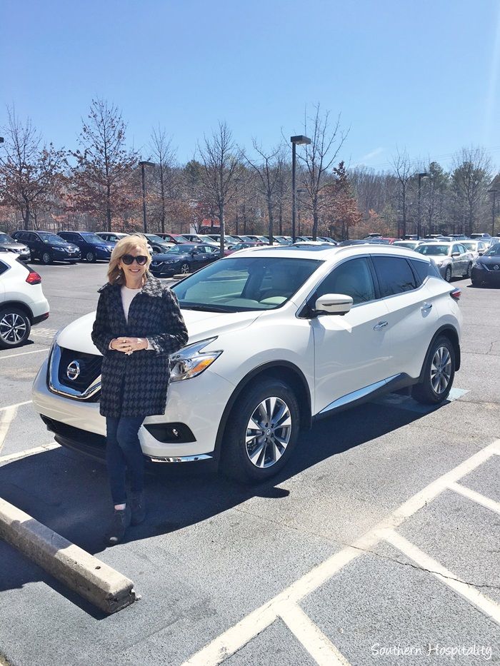 a woman standing next to a white car in a parking lot