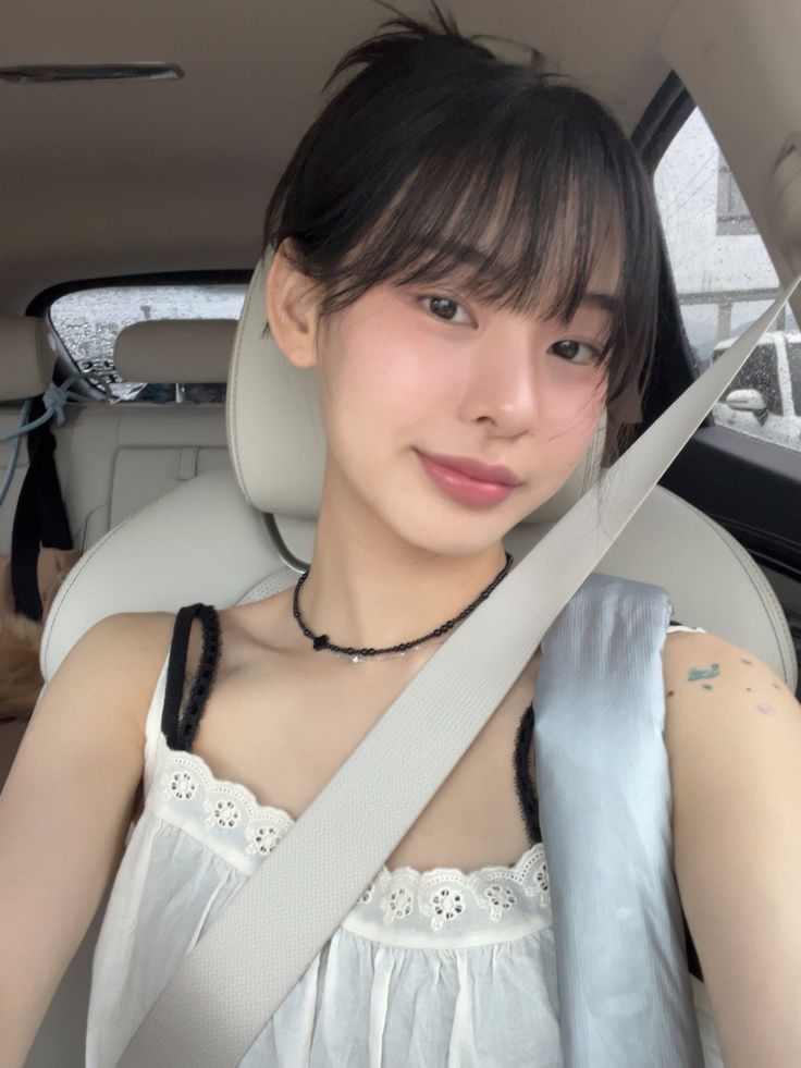 a young woman sitting in the back seat of a car holding onto a large pair of scissors