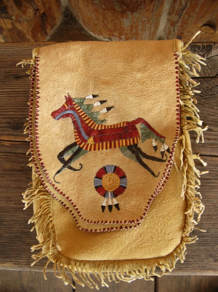 an embroidered bag with horses on it hanging from a wooden wall next to a potted plant