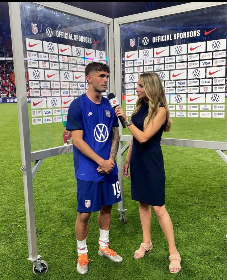 a man and woman talking to each other in front of a soccer goalie booth