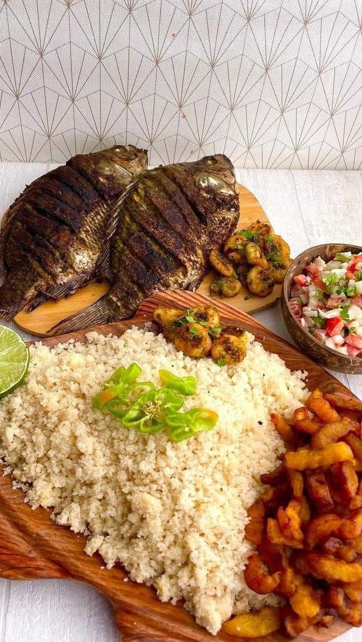 a wooden plate topped with rice and meat next to other foods on top of a table