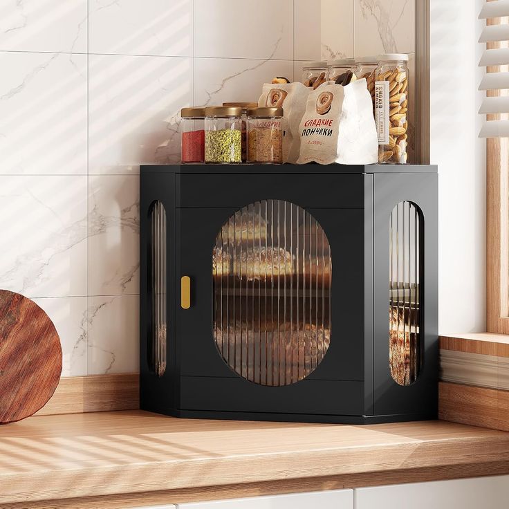 a black microwave oven sitting on top of a counter next to a wooden cutting board