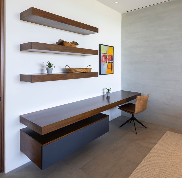 a room with some shelves on the wall and a desk in front of it,