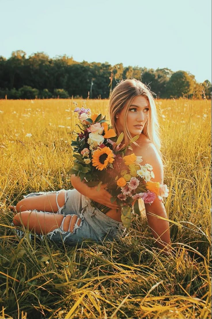 a woman sitting in the grass holding flowers