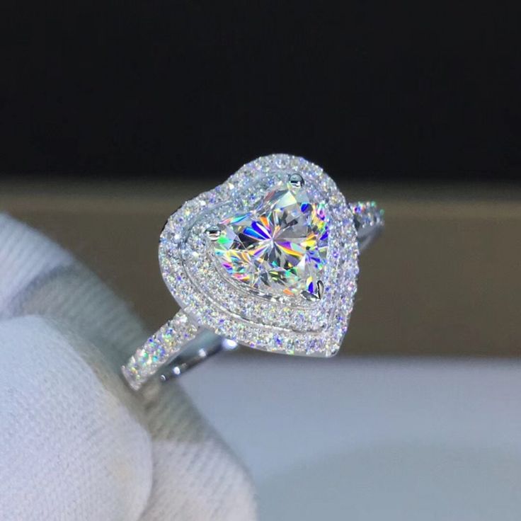 a close up view of a diamond ring on someone's finger, with the center stone surrounded by diamonds