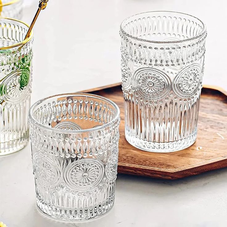 three clear glass cups sitting on top of a wooden tray