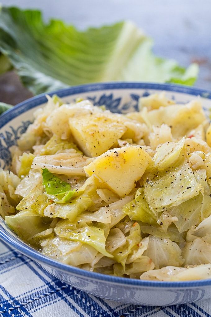 a bowl filled with cabbage and potatoes on top of a blue and white checkered table cloth