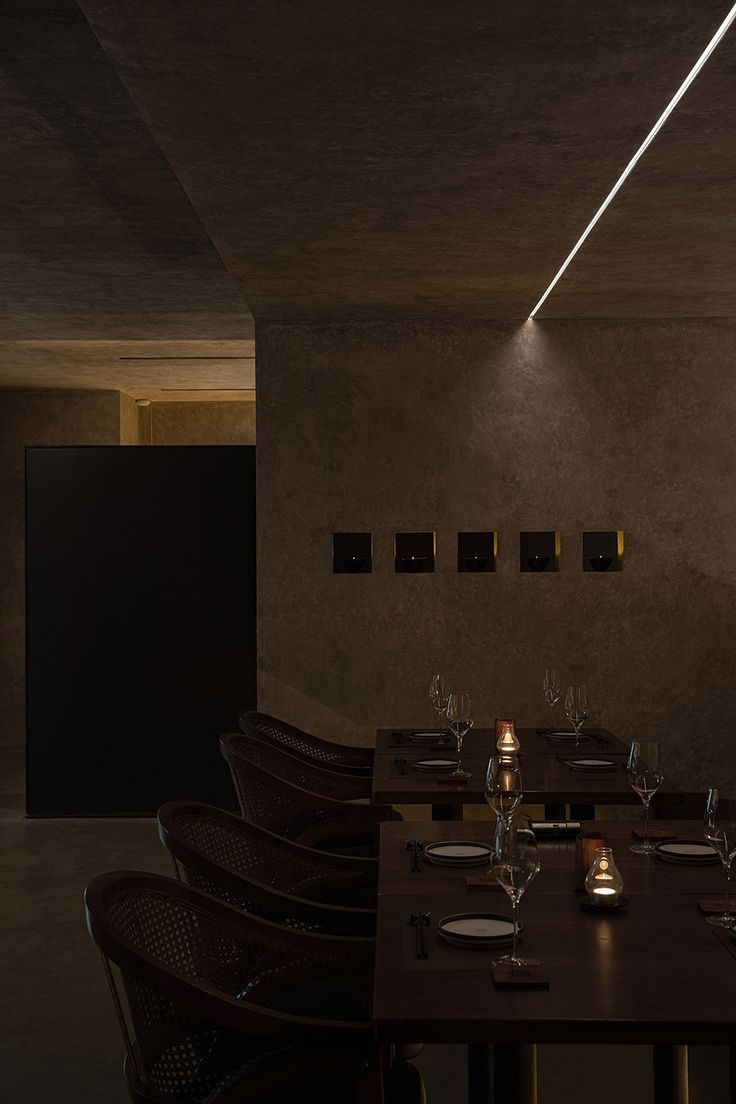 a dimly lit dining room with wooden tables and brown chairs is seen in this image