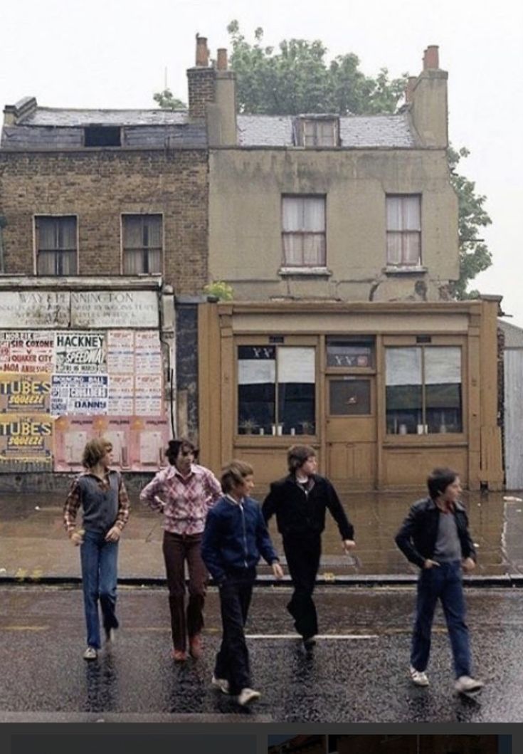 a group of people walking across a wet street