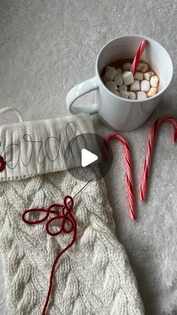 a cup of hot chocolate and candy canes on a white blanket next to a mug