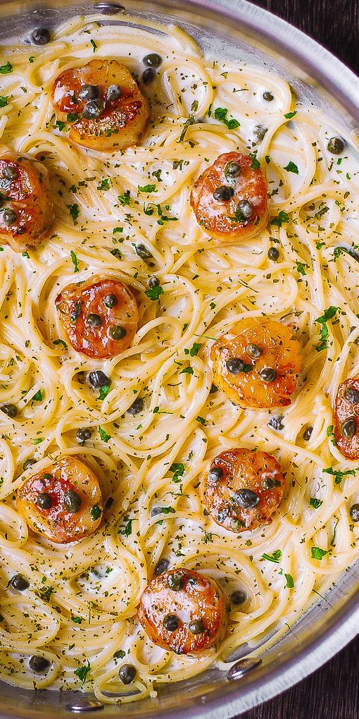 a pan filled with pasta topped with tomatoes and olives