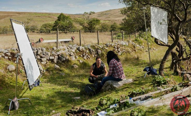 two people sitting in the grass near an easel