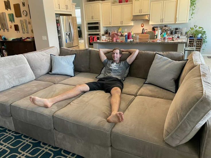 a man laying on top of a couch in a living room