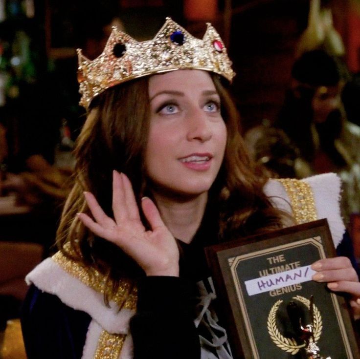 a woman wearing a tiara and holding an award in front of her face with both hands