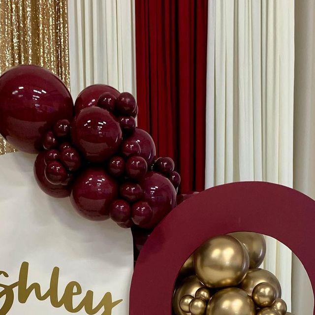 a bunch of balloons sitting on top of a table next to a white bag with gold balls