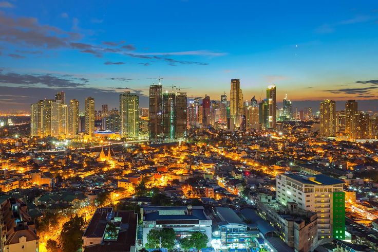 the city skyline is lit up at night with bright lights and skyscrapers in the background