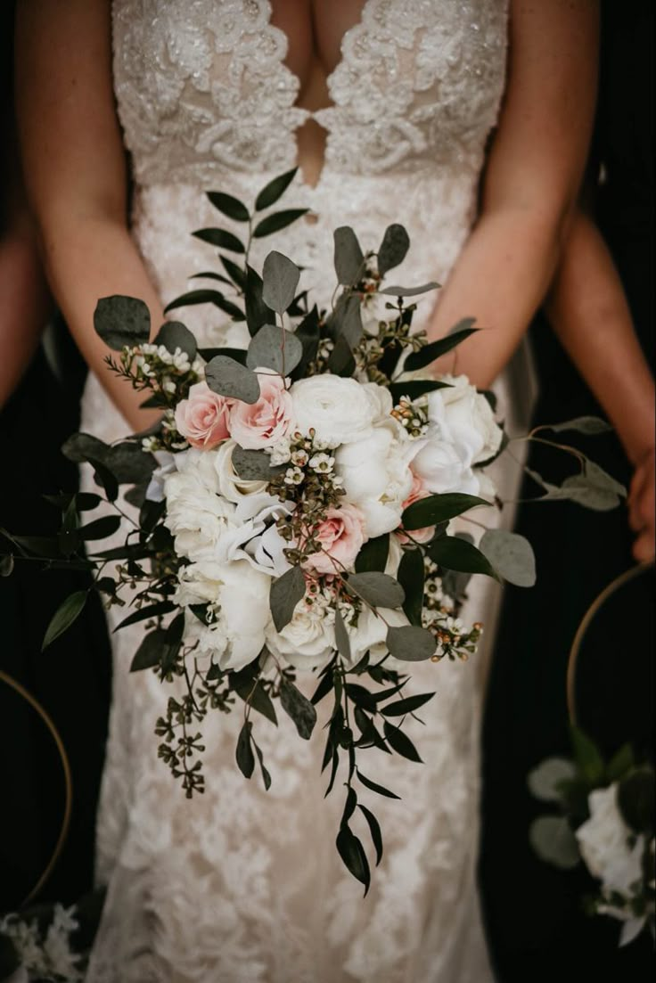 a bridal holding a bouquet of white and pink flowers with greenery on it