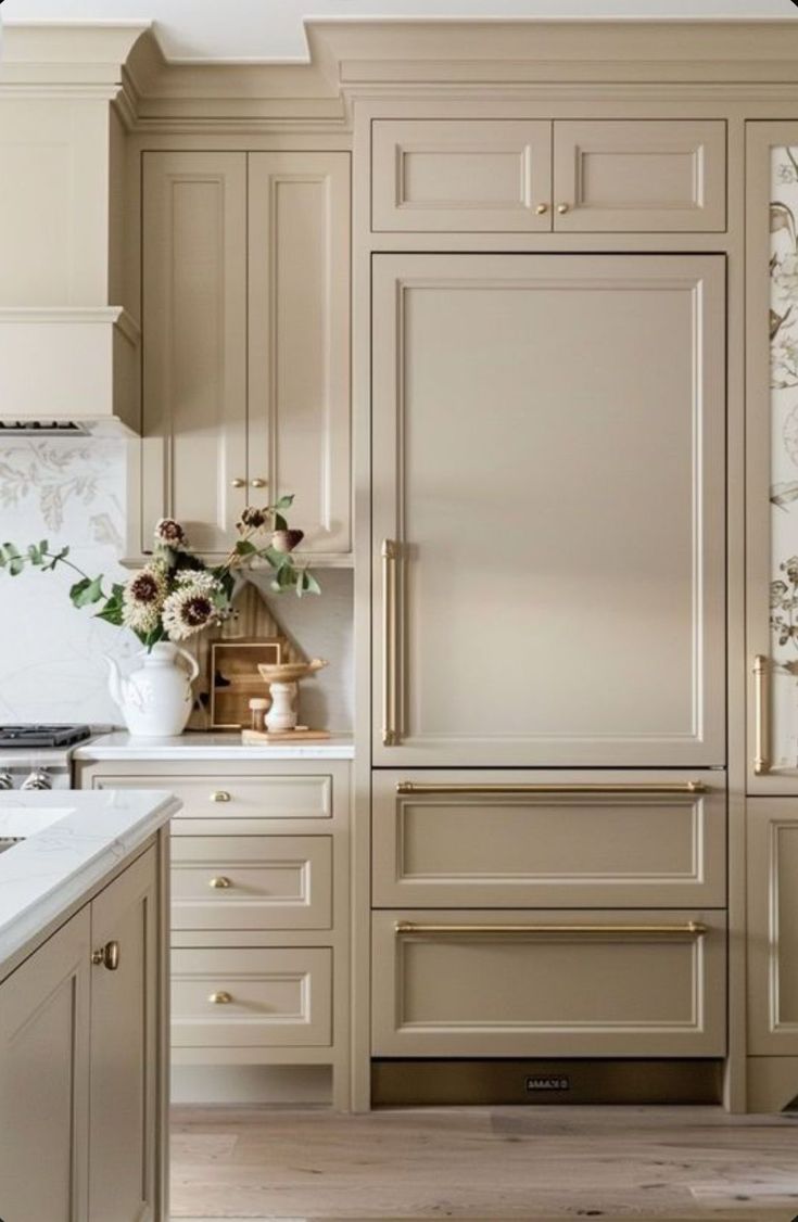 a kitchen with beige cabinets and white marble counter tops is pictured in this image, there are flowers on the cabinet doors