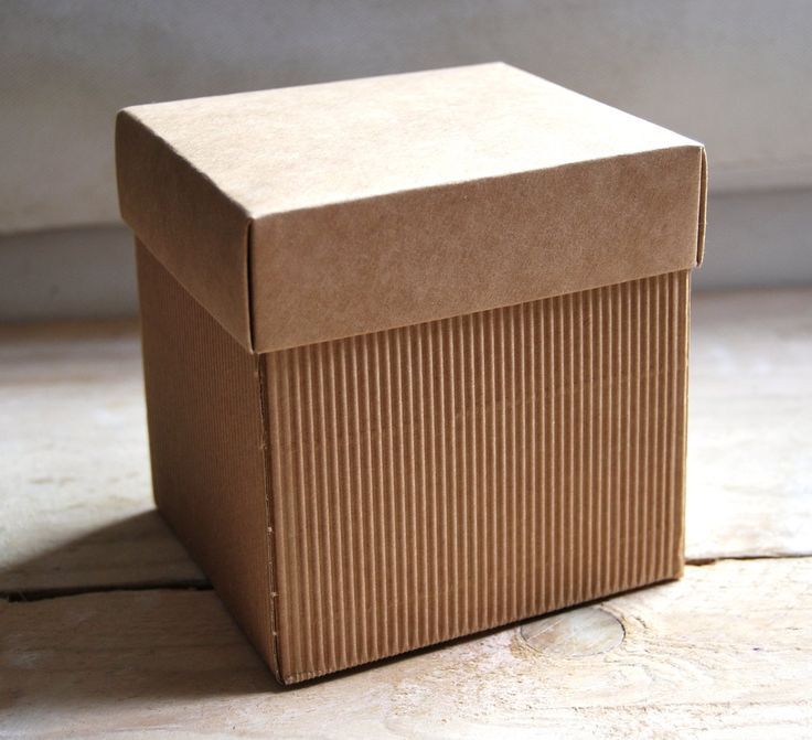 a brown box sitting on top of a wooden floor next to a white wall and window