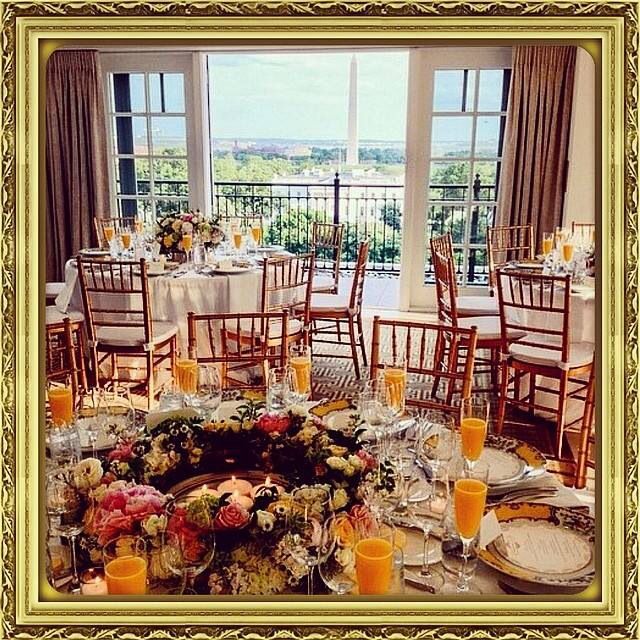 the table is set for an event with flowers and orange juices in front of large panoramic windows