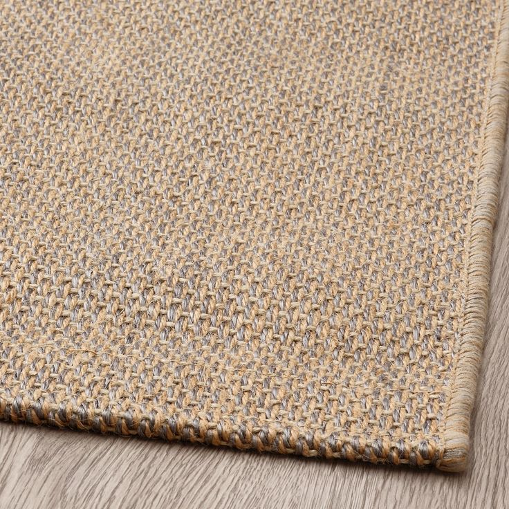 a close up view of a rug on the floor with wood and grass in the background