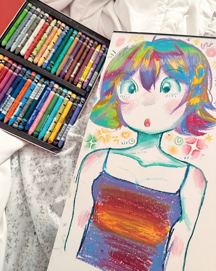 a drawing with crayons next to it on a bed