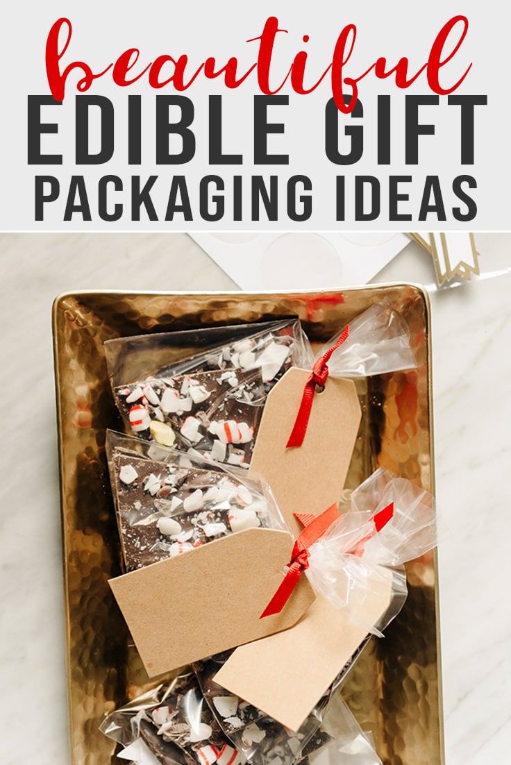 a gift box filled with chocolates and wrapped in red ribbon on top of a marble table