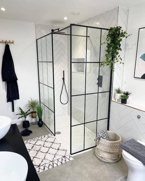 a bathroom with a shower, toilet and plants in it's corner area on the wall