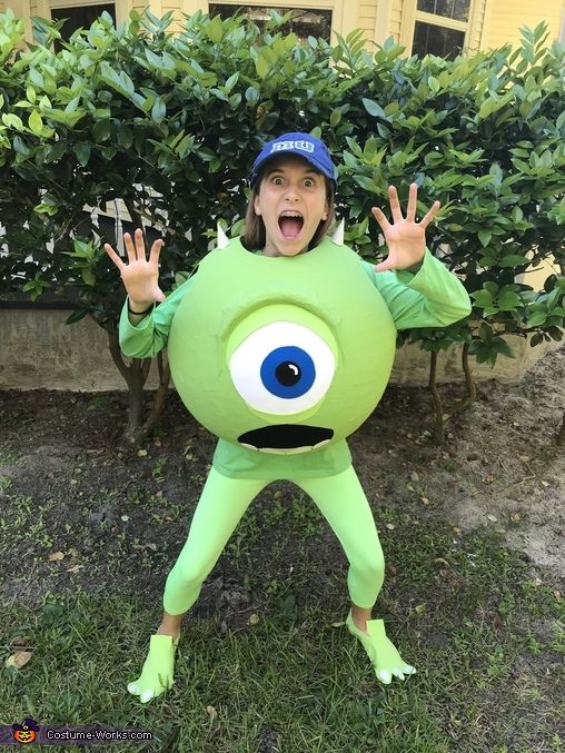 a young boy in a green costume with an evil eyeball on his chest and hands up