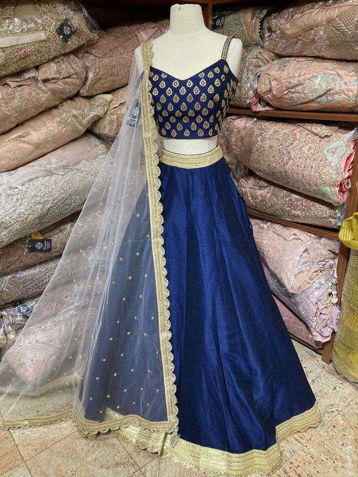 Navy blue plain lehenga with gold border teamed with beautiful cut dana and stone work blouse and contrasting ivory net dupatta. Fabric: Silk Occasion: Wedding Ceremony or Reception. WASH CARE INSTRUCTIONS - Please Dry clean only when it is applicable. Slight color variation is possible due to digital photography. This outfit can be customized in multiple colors and specific to client measurements. 120 days of production time is required and are for bulk orders only!Order are processed in store Blue Raw Silk Dupatta With Gota Work, Blue Art Silk Gown With Traditional Drape, Blue Floor-length Traditional Wear With Gota Work, Blue Raw Silk Gown With Zari Work, Traditional Blue Raw Silk Gown, Blue Raw Silk Salwar Kameez For Reception, Blue Raw Silk Choli With Gota Work, Blue Anarkali Set With Gota Work For Wedding, Blue Lehenga With Gota Work For Eid