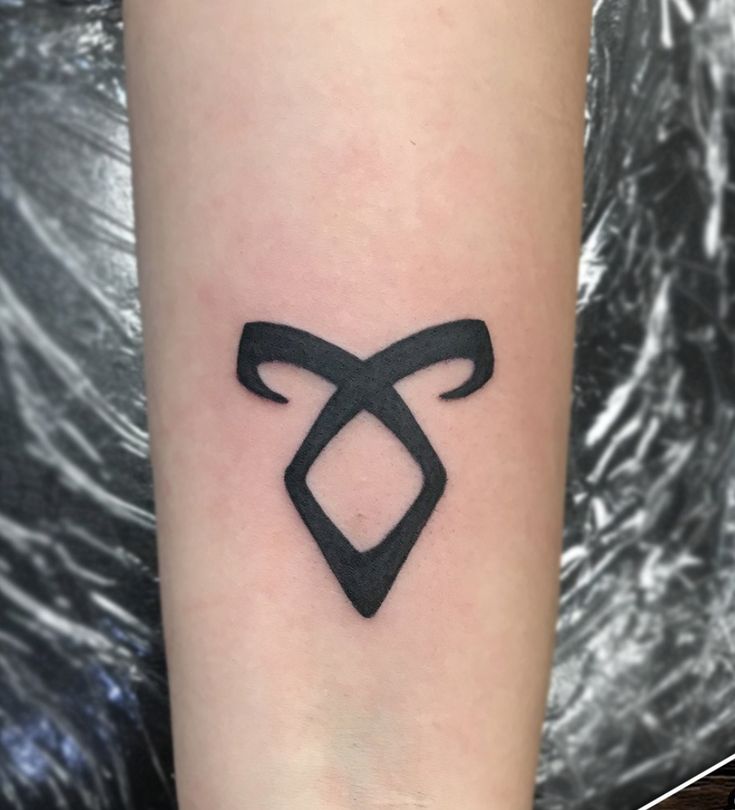 a small black bow tattoo on the arm