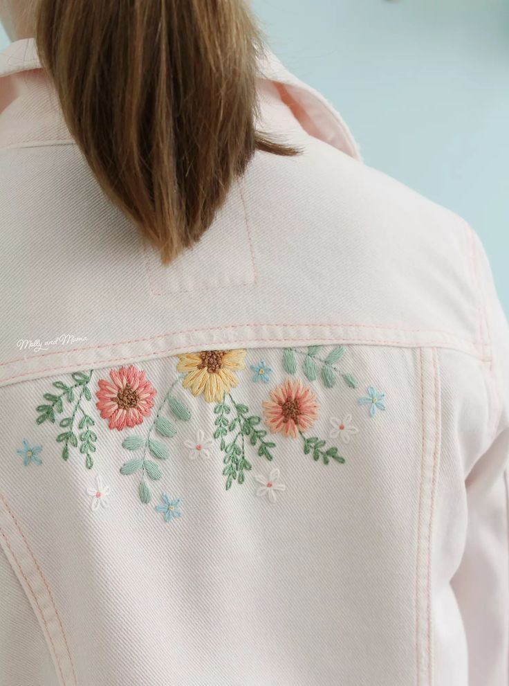 the back of a woman's jacket with flowers embroidered on it