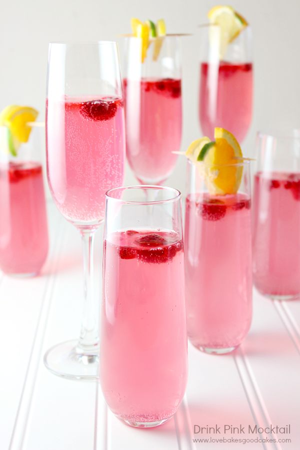 several glasses filled with pink liquid and lemon wedges next to each other on a white table