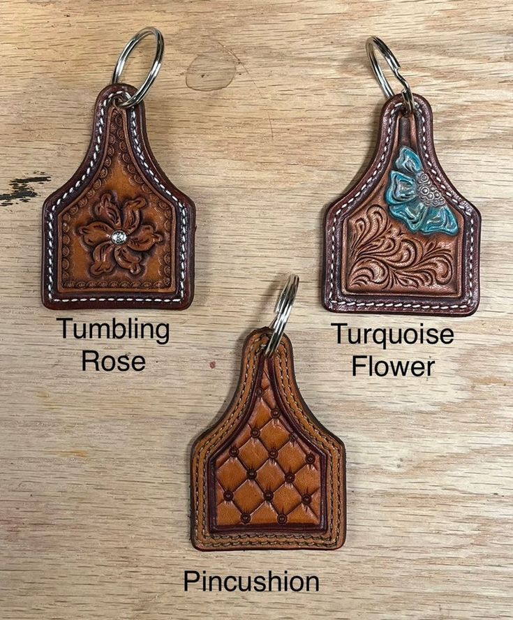 three different types of leather keychains on a wooden surface, with the names and description