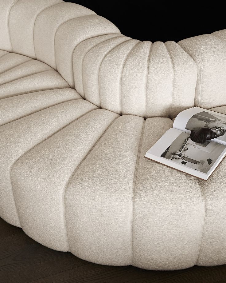 a magazine sitting on top of a white leather couch cushioned to the back of a chair