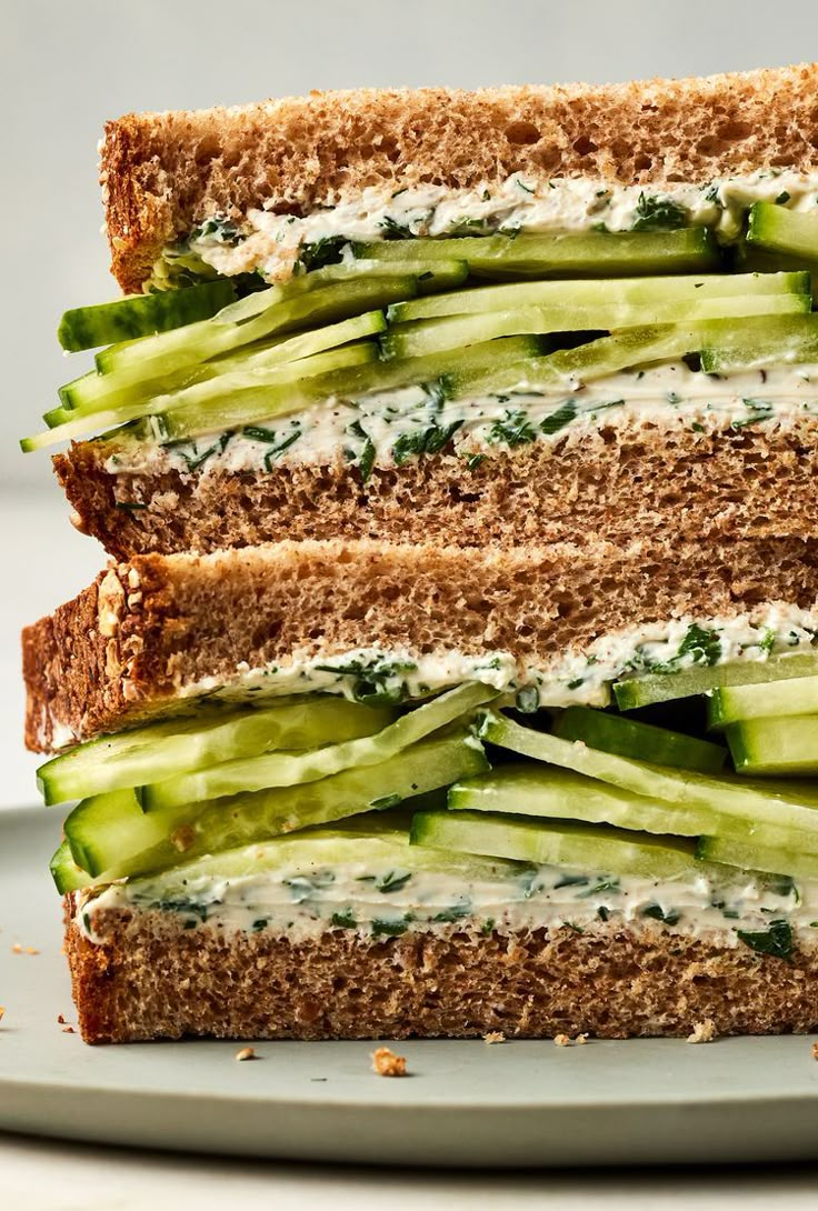 a close up of a sandwich on a plate with cheese and cucumber slices