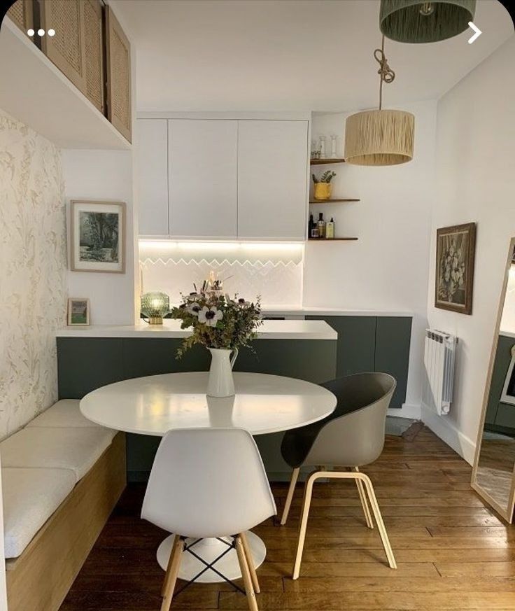 a white table and chairs in a small room with wood flooring on the side