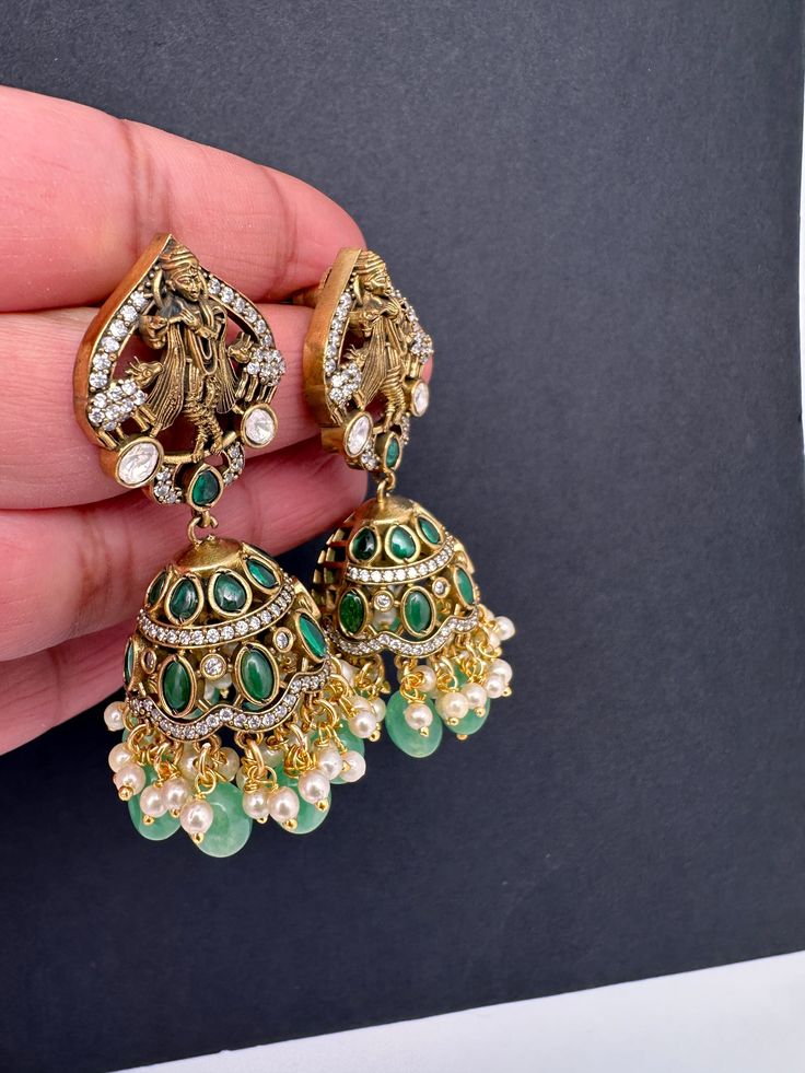 Krishna Jhumki Earrings pushback earringsColor : VictorianSize : Length : 2.5 Inches; Weight : 18grams eachStones : Red Green Stones Pearls Beads Green Hand-set Jhumkas For Festive Occasions, Fusion Style Earrings With Latkans For Festivals, Festive Green Hand-set Jhumkas, Fusion Kundan Jhumkas Drop Earrings, Kundan Fusion Jhumkas, Fusion Style Kundan Jhumkas, Festive Jhumkas With Peacock Design, Green Stone Work Temple Jewelry Earrings, Temple Jewelry Jhumkas For Party