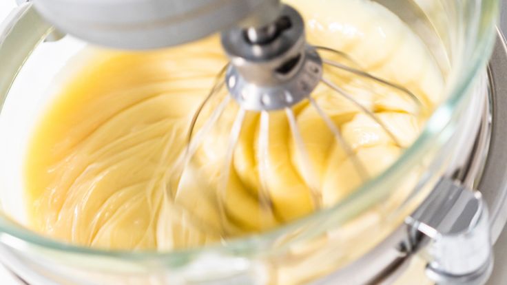 a food processor filled with yellow liquid and whisk