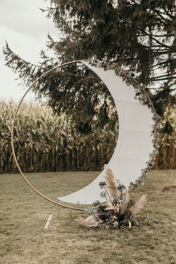 a large white moon sitting on top of a lush green field next to a tall tree