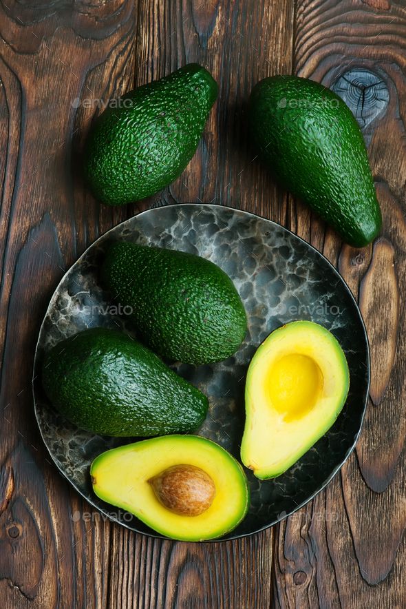 an avocado cut in half on a plate with two halves and one whole